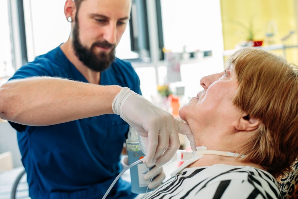 Männliche Pflegefachkraft schließt eine Inhalation an eine Trachealkanüle an